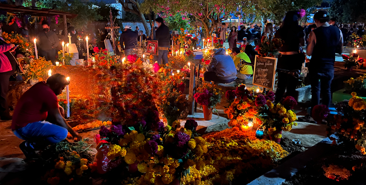 Tombes éclairées par des bougies et couvertes de fleurs pendant le Día de Muertos à Oaxaca