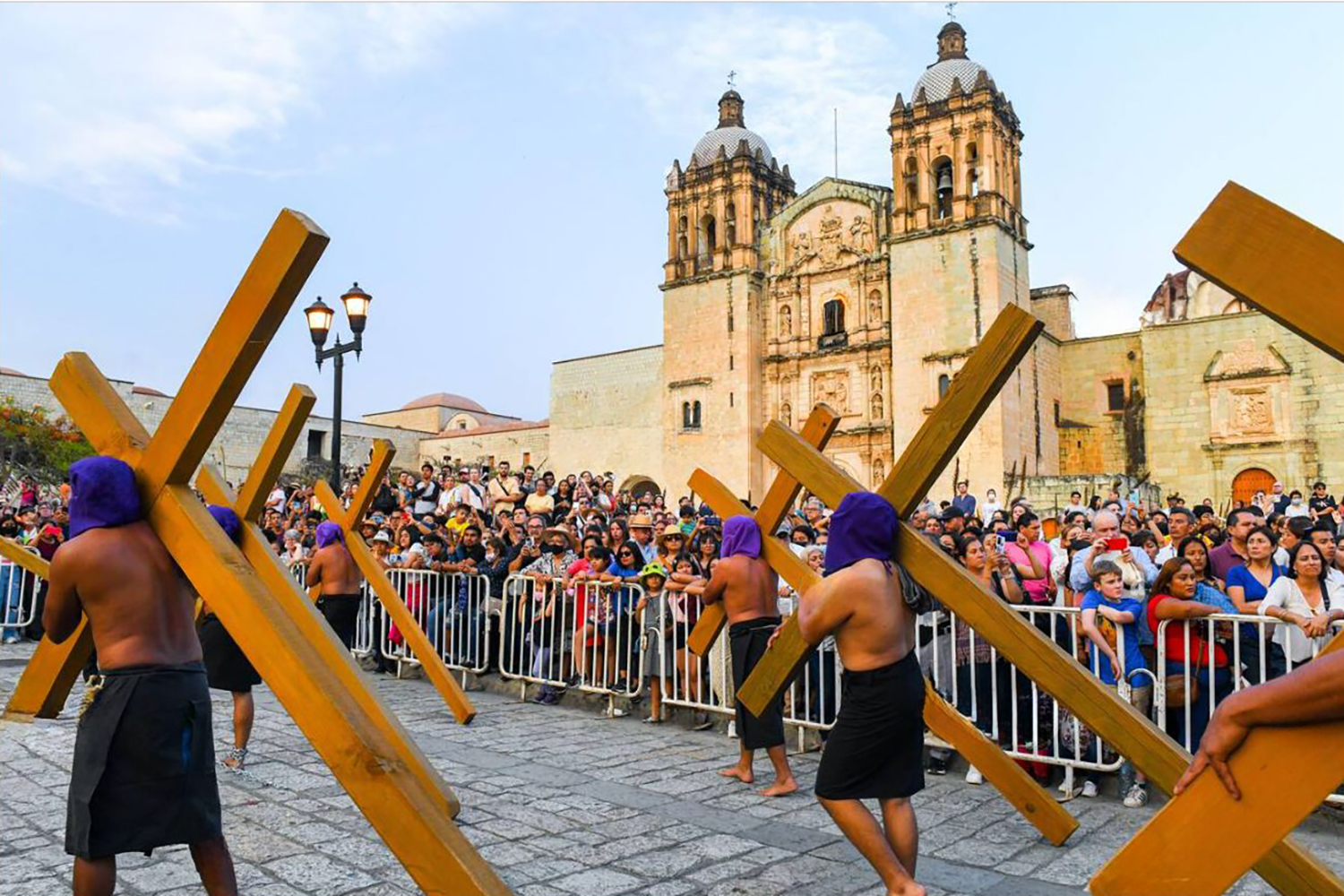 Hombres encapuchados cargan cruces durante una procesión silenciosa de Viernes Santo.