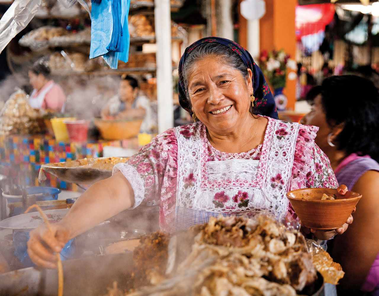 Mercado de comida concurrido con carnes asadas y platillos locales